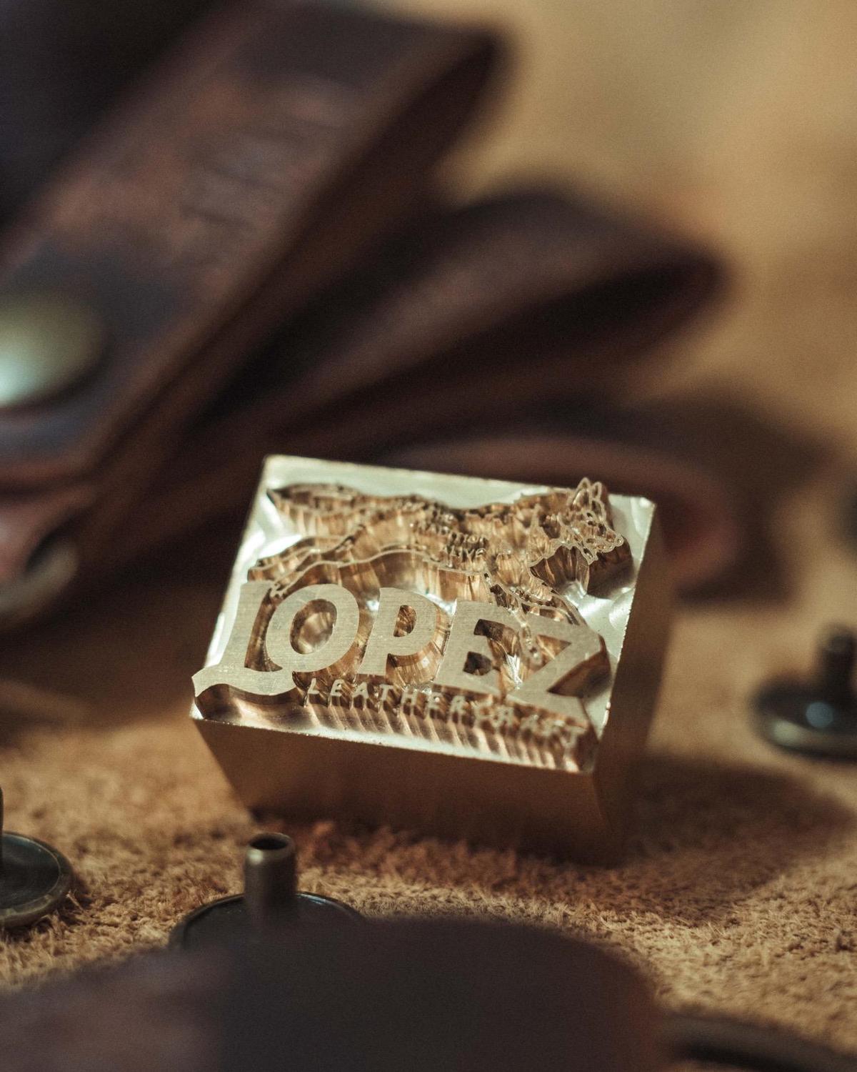 The Lopez Leathercraft brass stamp, the running wolf and wordmark milled in relief
