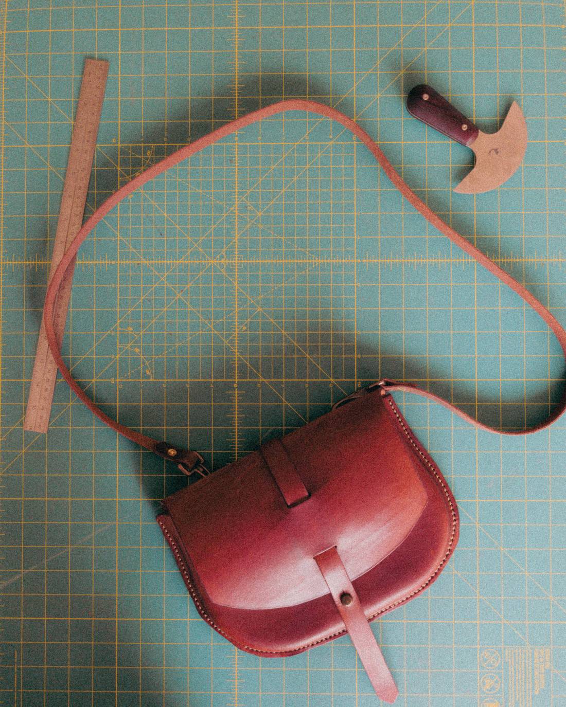 A leather crossbody bag in progress on the workbench cutting mat